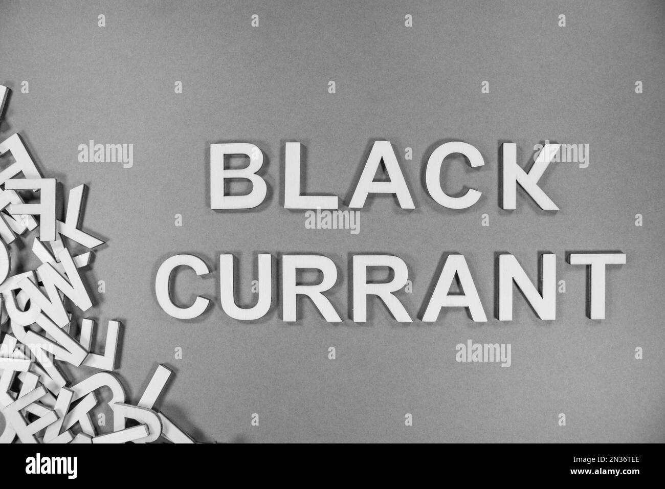 BLACK CURRANT fruit in wooden English language capital letters spilling from a pile of letters in black and white Stock Photo