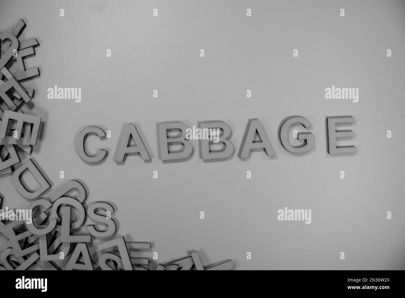 CABBAGE in wooden English words language capital letters spilling from a pile of letters in black and white Stock Photo