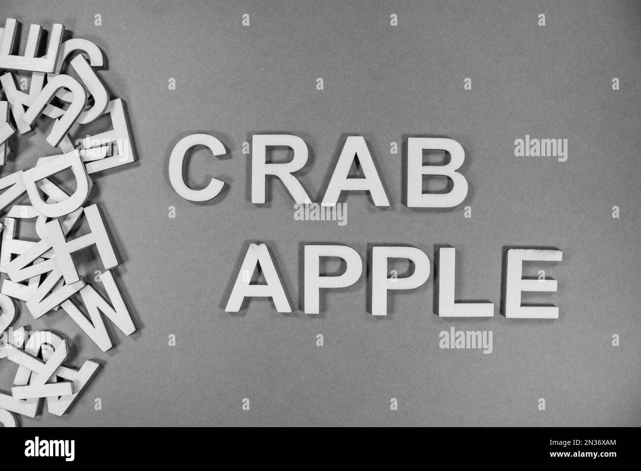 CRAB APPLE fruit in wooden English language capital letters spilling from a pile of letters in black and white Stock Photo
