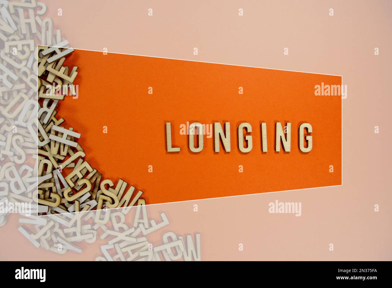 LONGING in wooden English language capital letters spilling from a pile ...