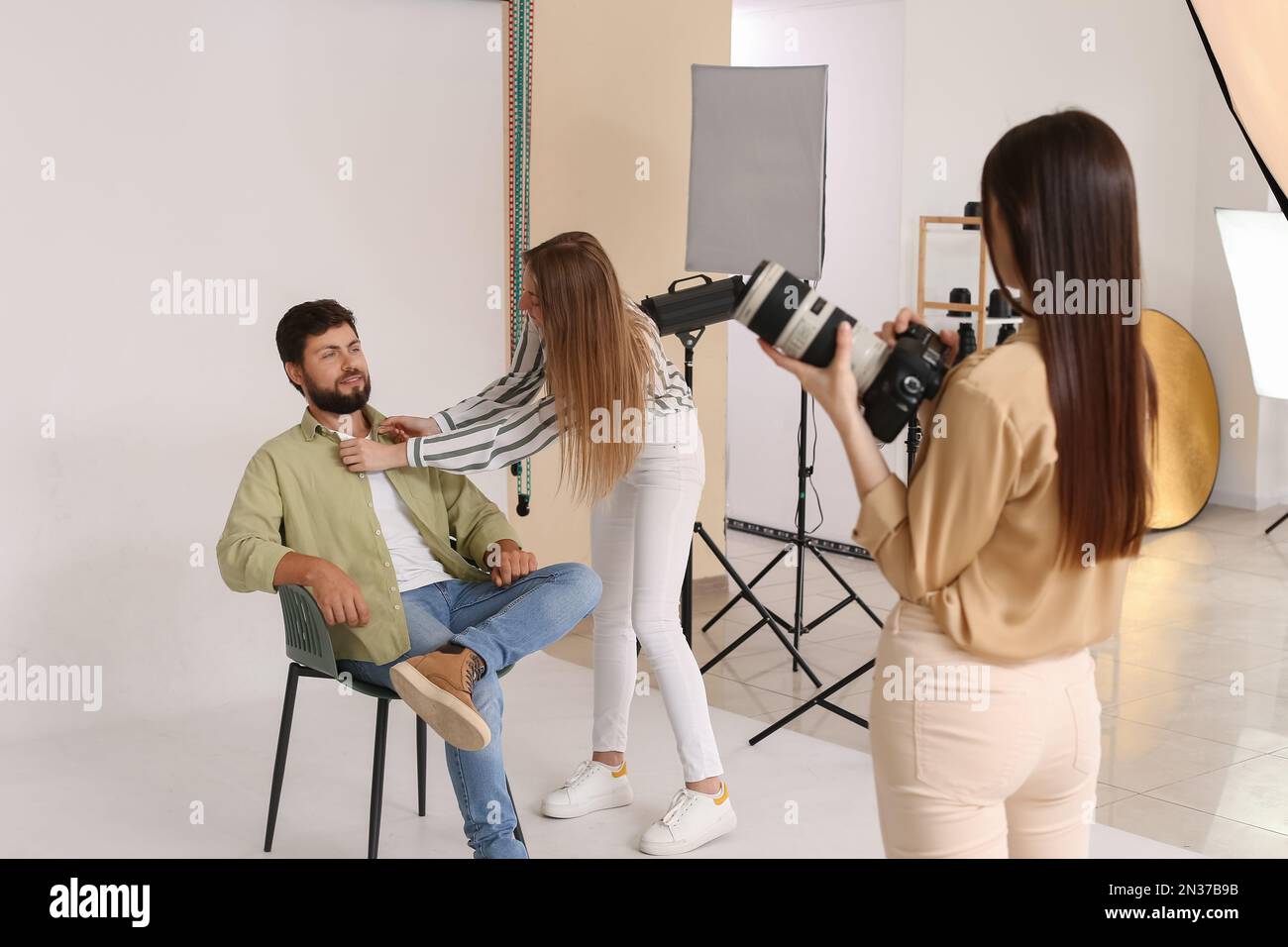 Female photographer and her assistant working with handsome model in ...