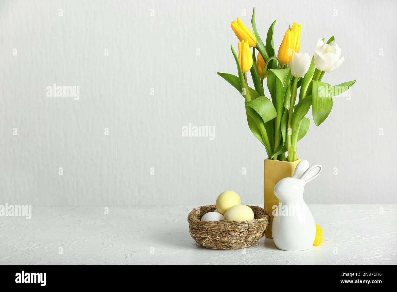 Vase with beautiful tulip flowers, nest of Easter eggs and ceramic ...