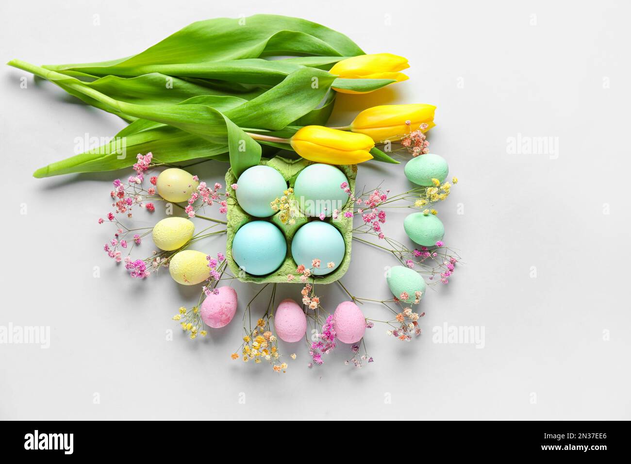 Composition with painted Easter eggs and flowers on white background ...