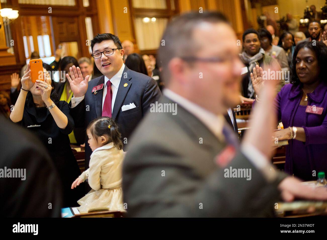 State Rep. B.J. Pak. R - Lilburn, left, is sworn in while joined by his wife  Sandra and daughter Natalia, 2, on the House Floor on the first day of the  Georgia