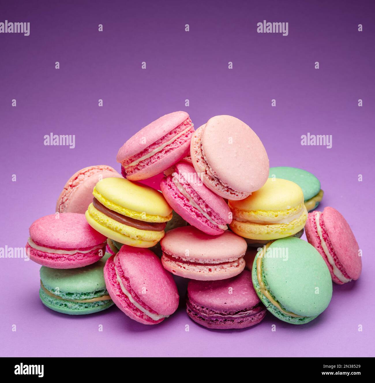 Colorful sweet macarons or macaroons, flavored cookies on purple ...