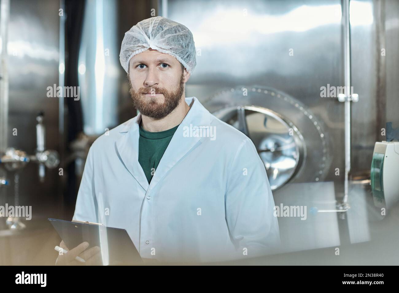 Waist up portrait of male worker wearing lab coat standing at food