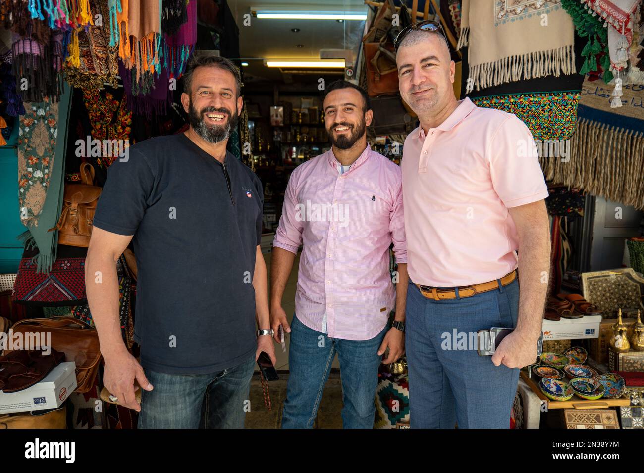 Bethlehem, West Bank, Palestine - 21 July 2022: Three Arab Men Smile and Pose Together In Front of Different Merchandise of a Handcraft and Souvenir S Stock Photo