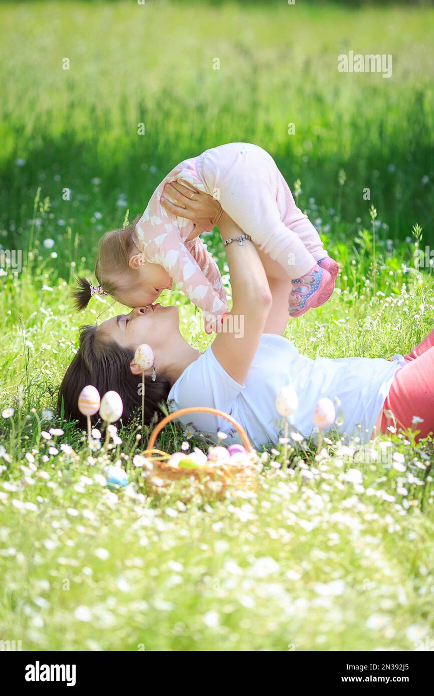 Happy mother and little child hugging kissing in spring park on nature