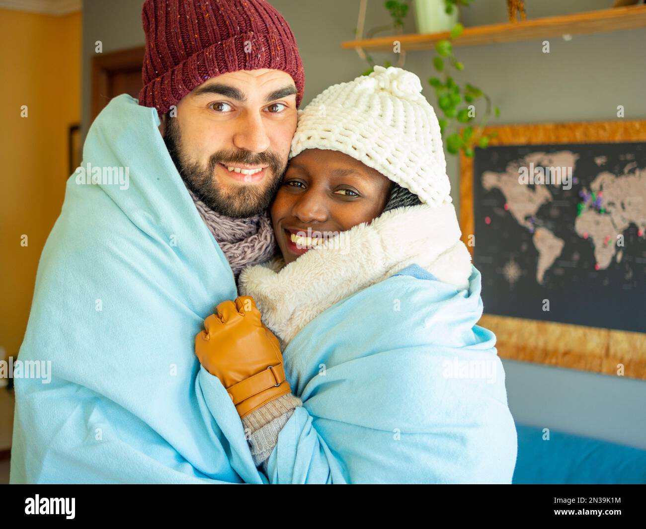 Young couple sharing a blanket to fight cold wave. Wearing winter