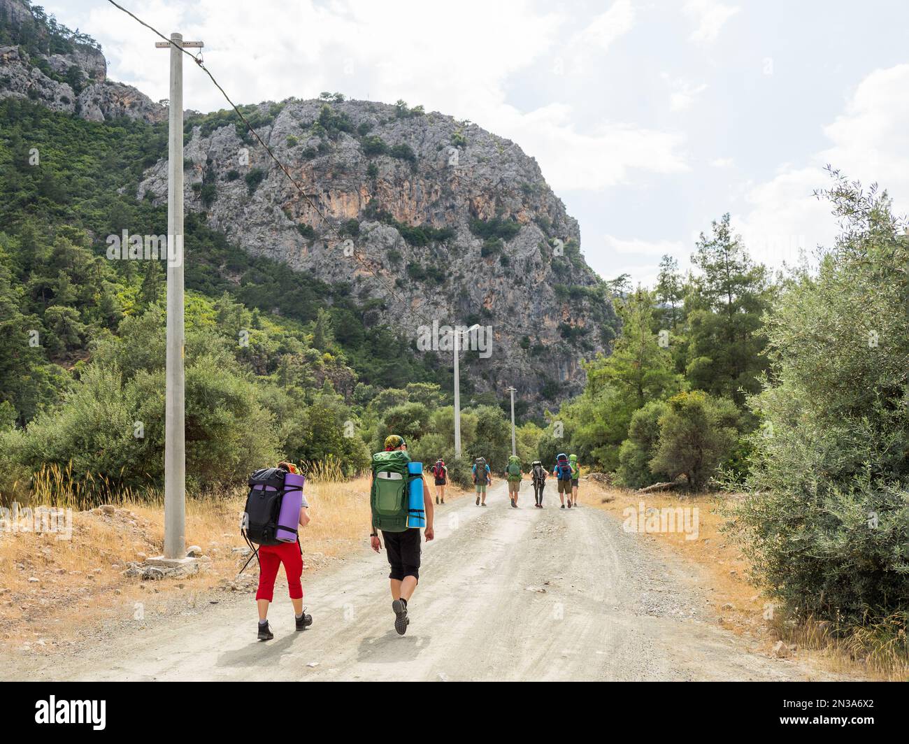 Tourists with backpacks walk to Goynuk Canyon. Path along mountain slopes in Beydaglari Coastal National Park. Turkey. Stock Photo