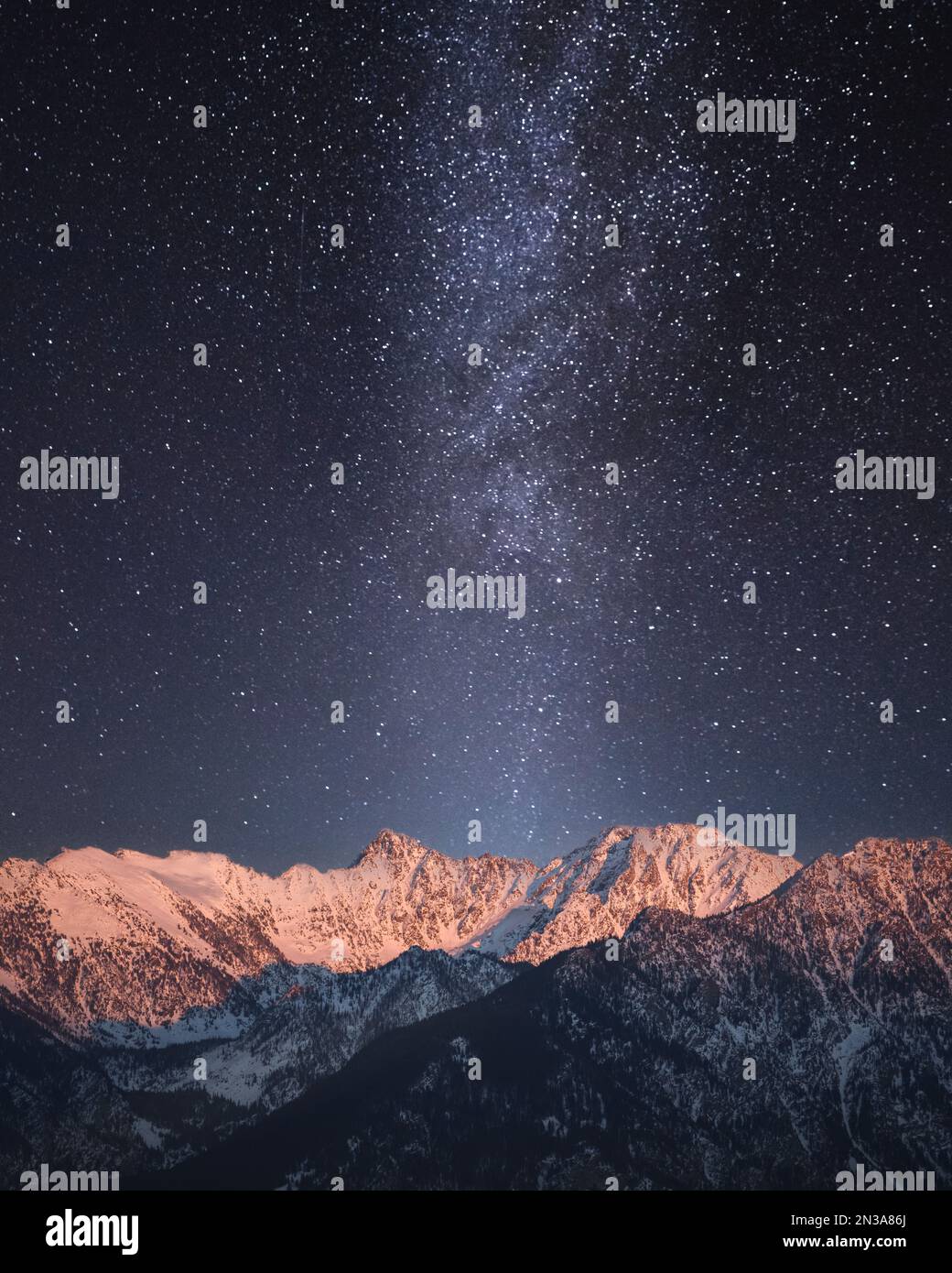 A starry night sky and Milky Way over snowy mountains Stock Photo - Alamy