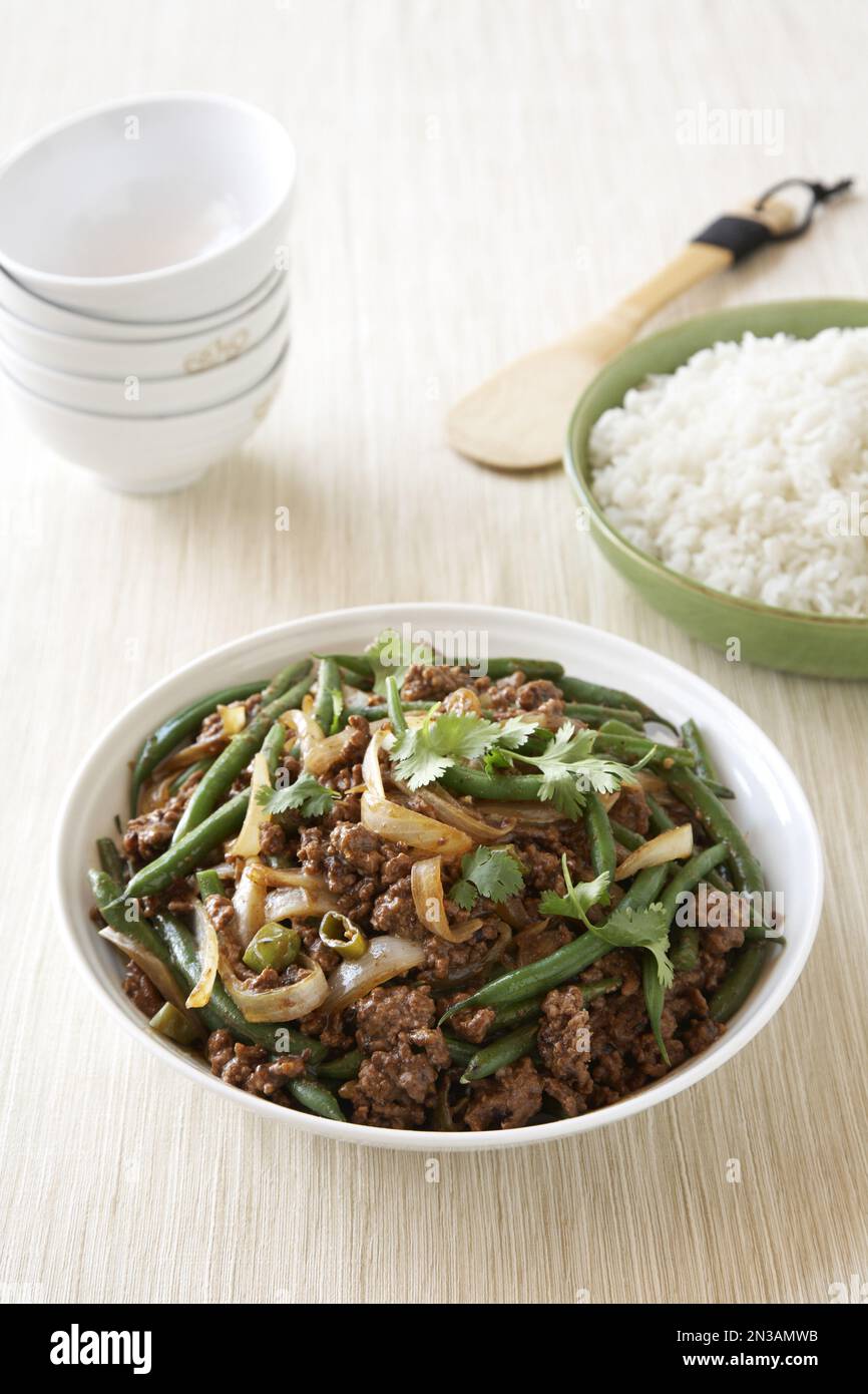 Ground beef stir fry with green beans and onions in white bowl with ...