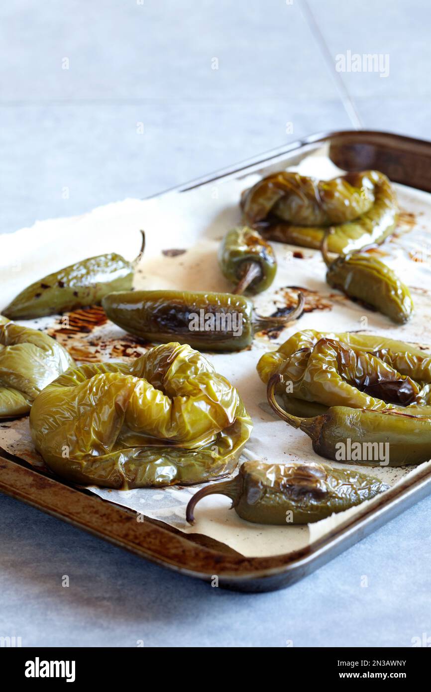 Roasted green peppers and jalapenos on a parchment paper lined baking