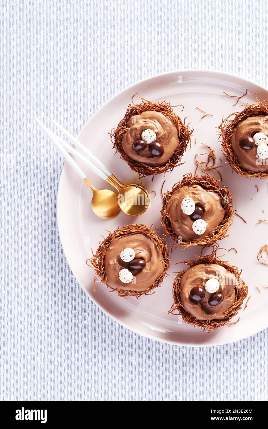 Plate of chocolate mousse nest cups with chocolate egg garnish and gold colored spoons Stock Photo