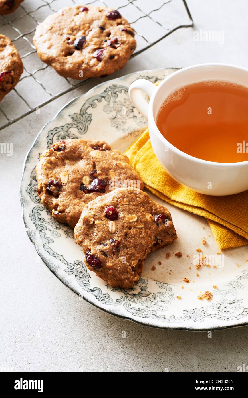 Cranberry oat breakfast cookies on a decorative plate with a cup of herbal tea Stock Photo