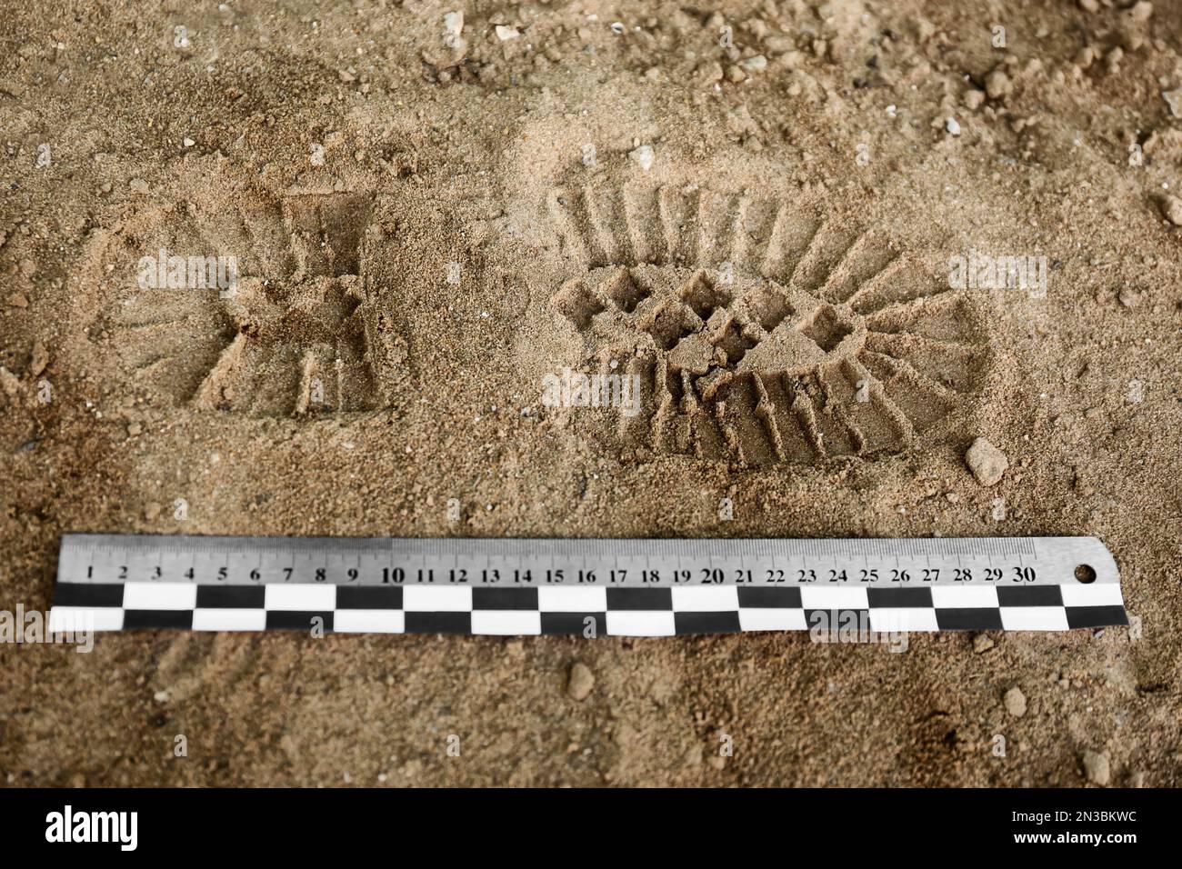 Ruler near footprint on sand, top view. Crime scene investigation and ...