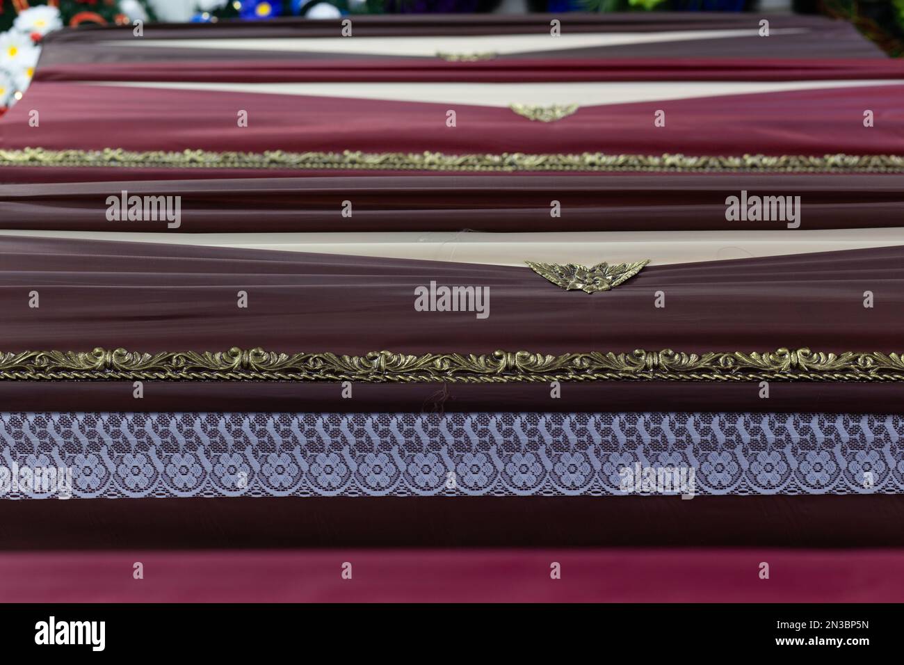 Background of coffin lids in a funeral goods store. Coffin lids are decorated with decorative elements and trimmed with fabric. Stock Photo