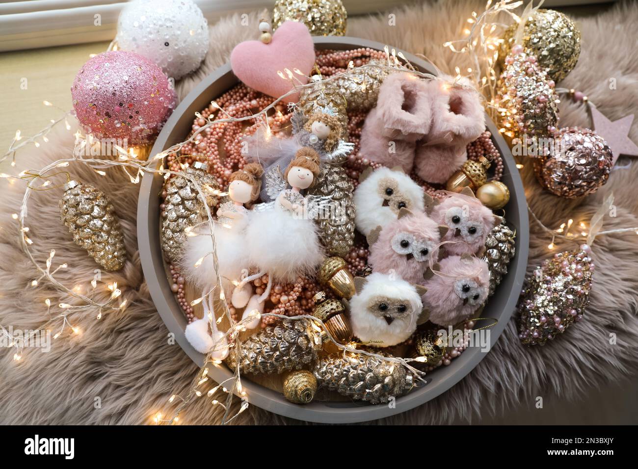 Beautiful Christmas tree baubles, toys and fairy lights on faux fur, flat lay Stock Photo
