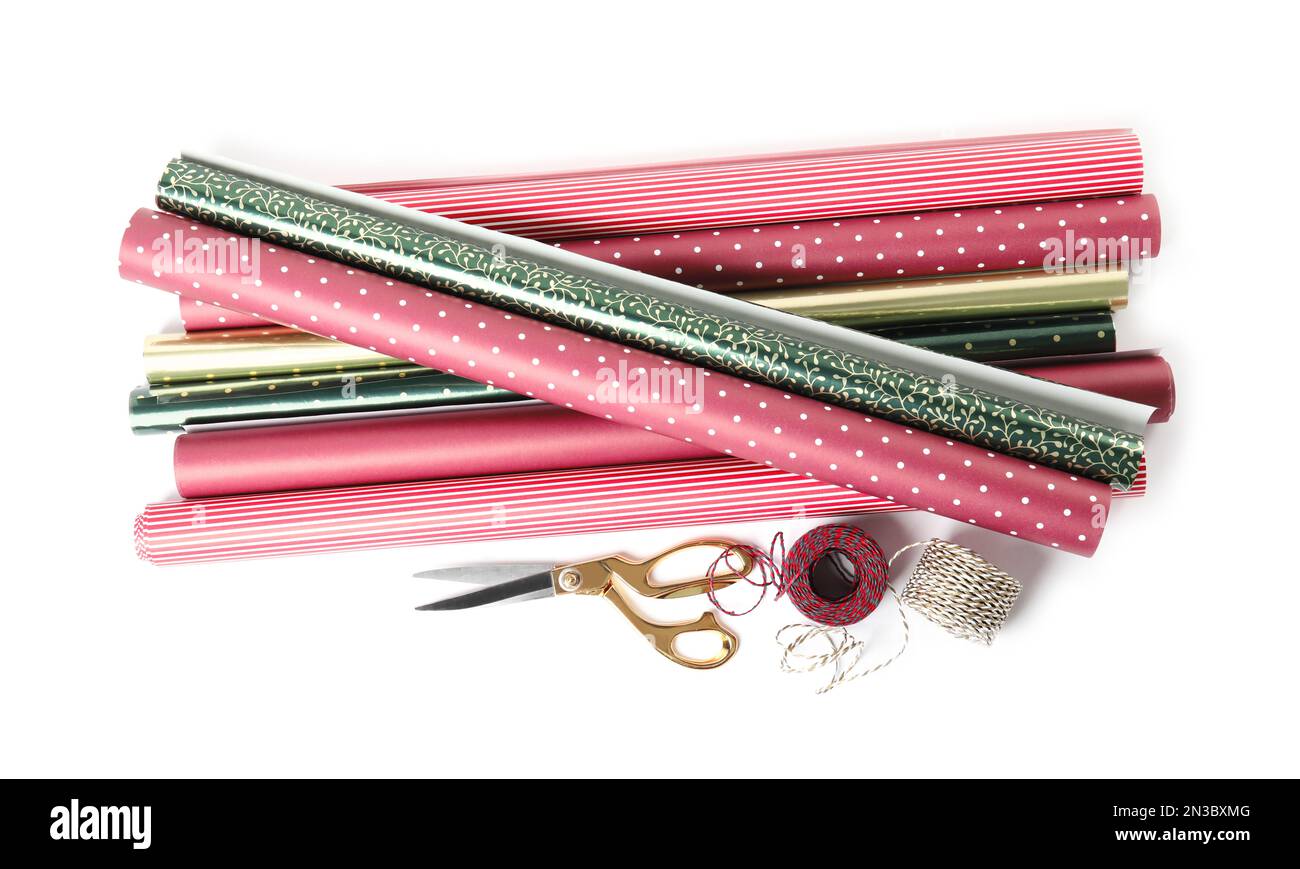 Different colorful wrapping paper rolls, scissors and ropes on white