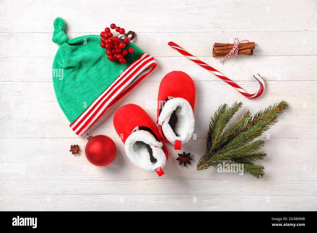 Cute baby booties, small elf hat and Christmas decorations on white