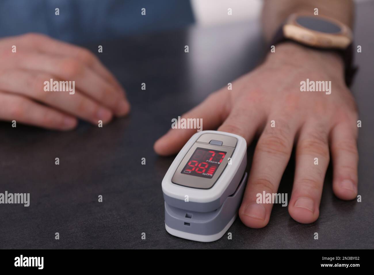 Man measuring oxygen level with modern fingertip pulse oximeter at grey