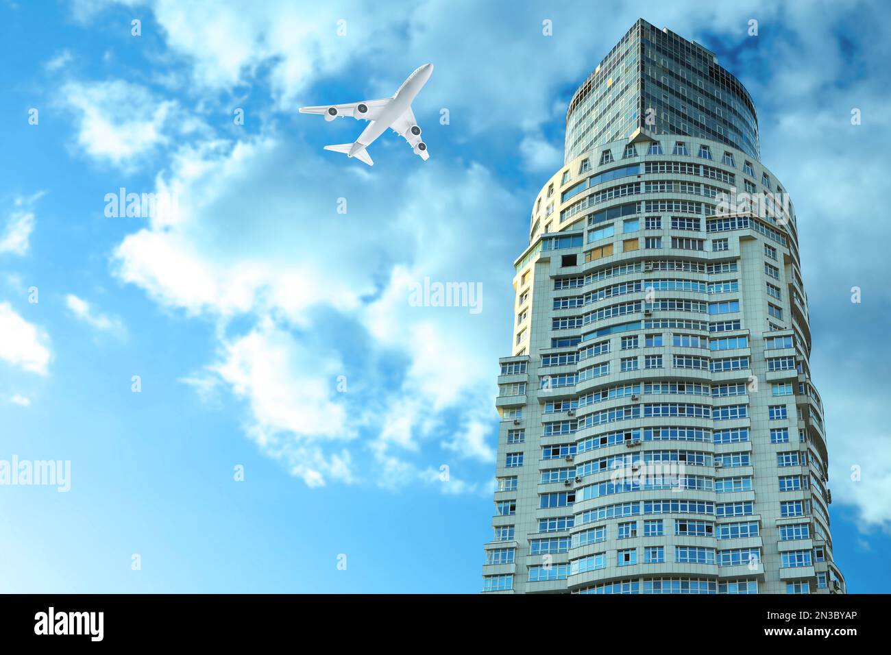Airplane flying in blue sky over skyscraper Stock Photo - Alamy