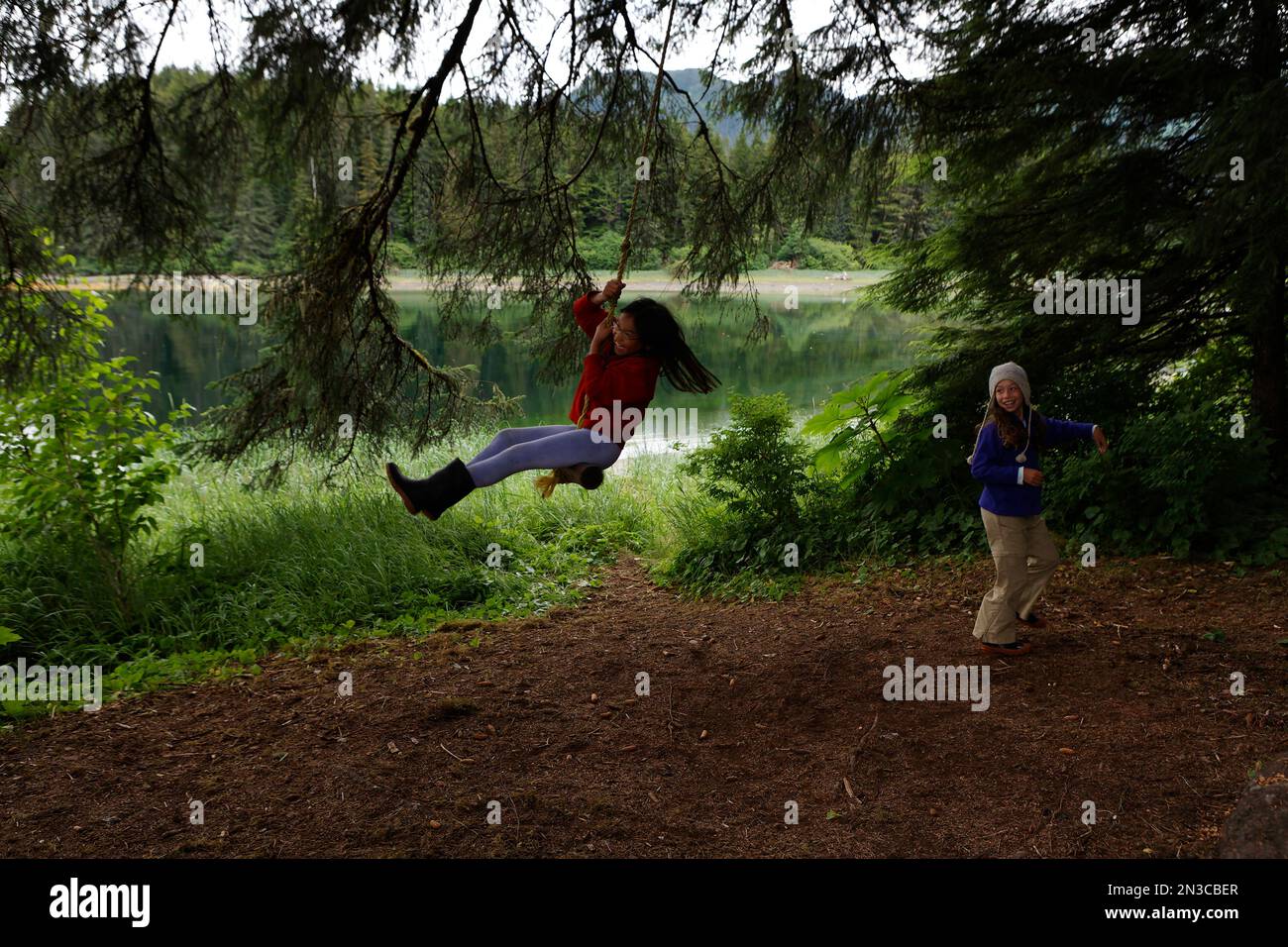 Two female friends Friends play on a rope swing on an island in the ...