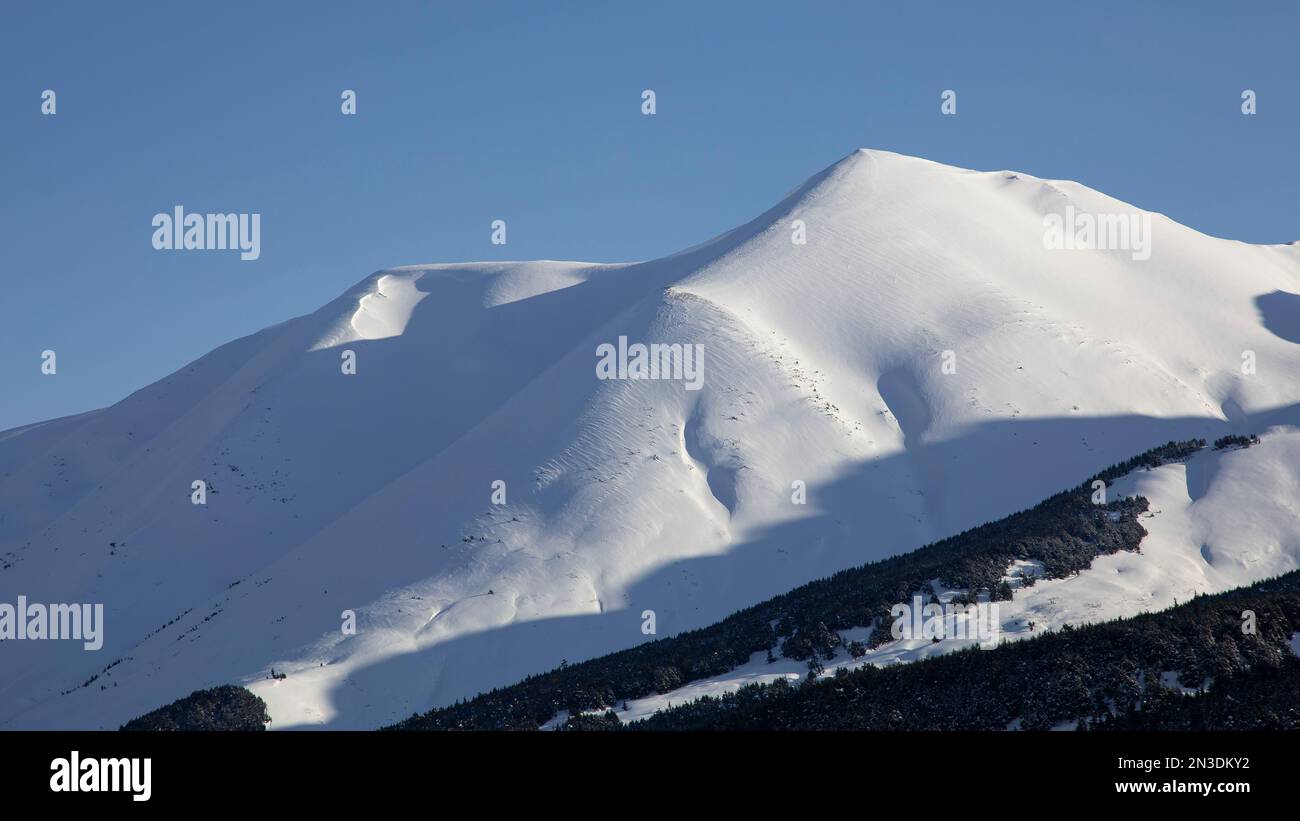 Snow covered mountain peaks against a bright blue sky in the Chugach National Forest; Alaska, United States of America Stock Photo
