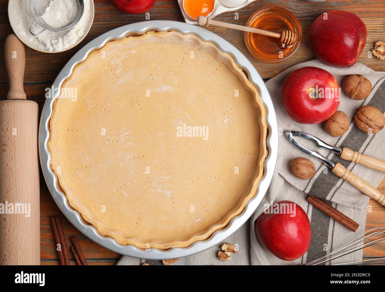 Raw dough and ingredients for traditional English apple pie on wooden table, flat lay Stock Photo