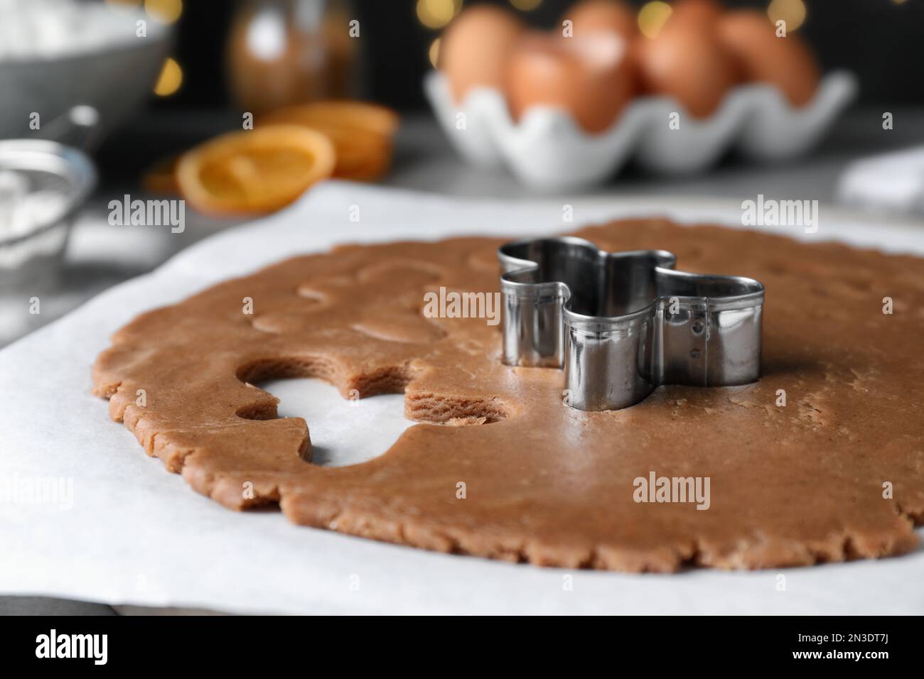 Making homemade Christmas cookies. Dough for gingerbread man and cutter on parchment, closeup Stock Photo