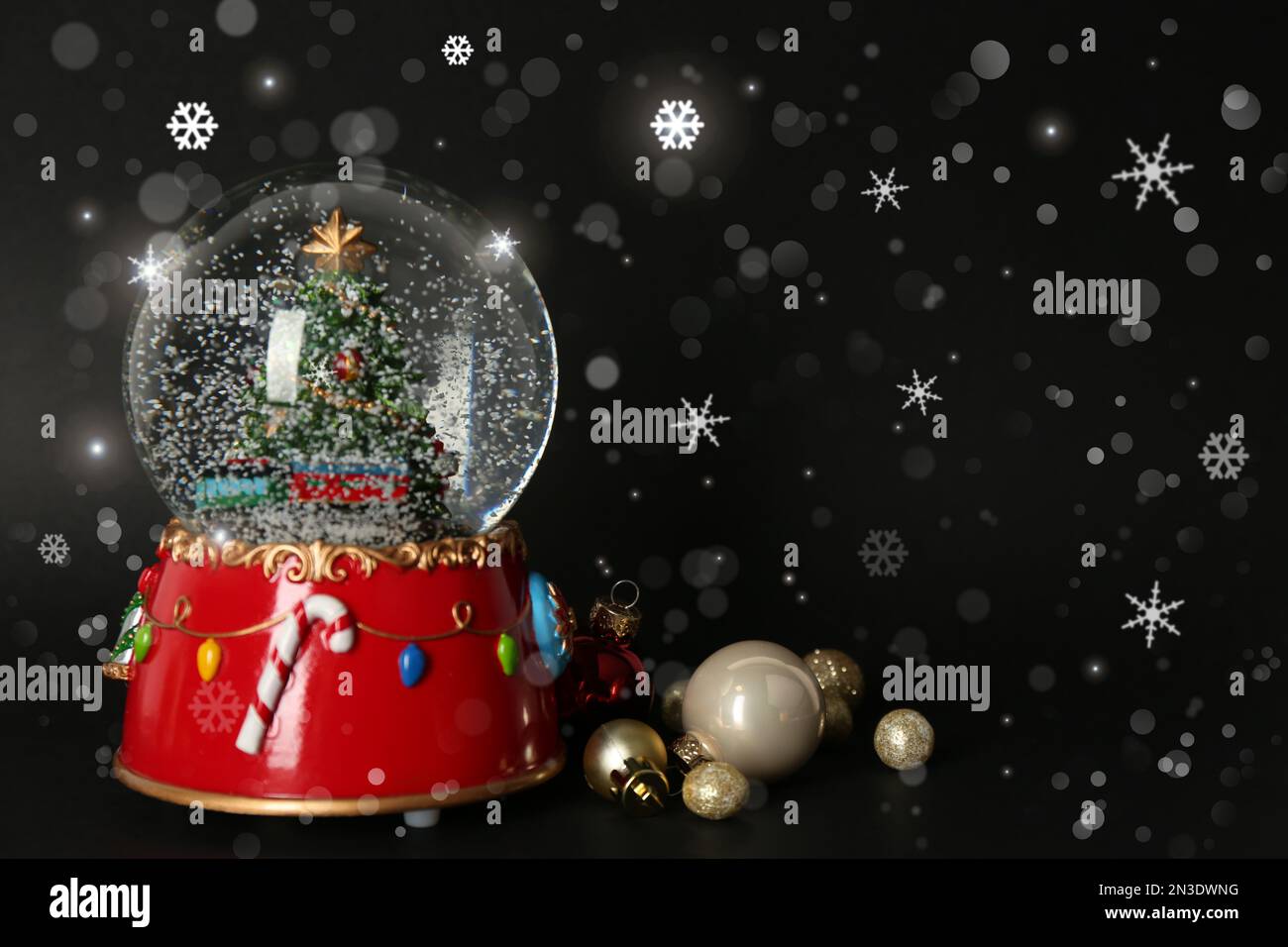 Beautiful snow globe and Christmas balls on black background, space for
