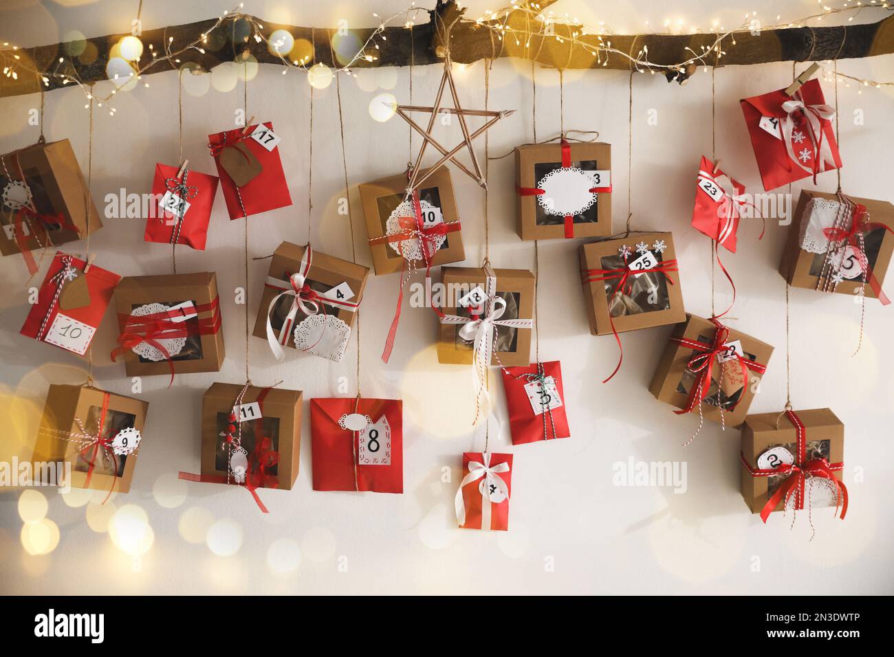 Handmade Advent calendar with gifts hanging on white wall. Christmas