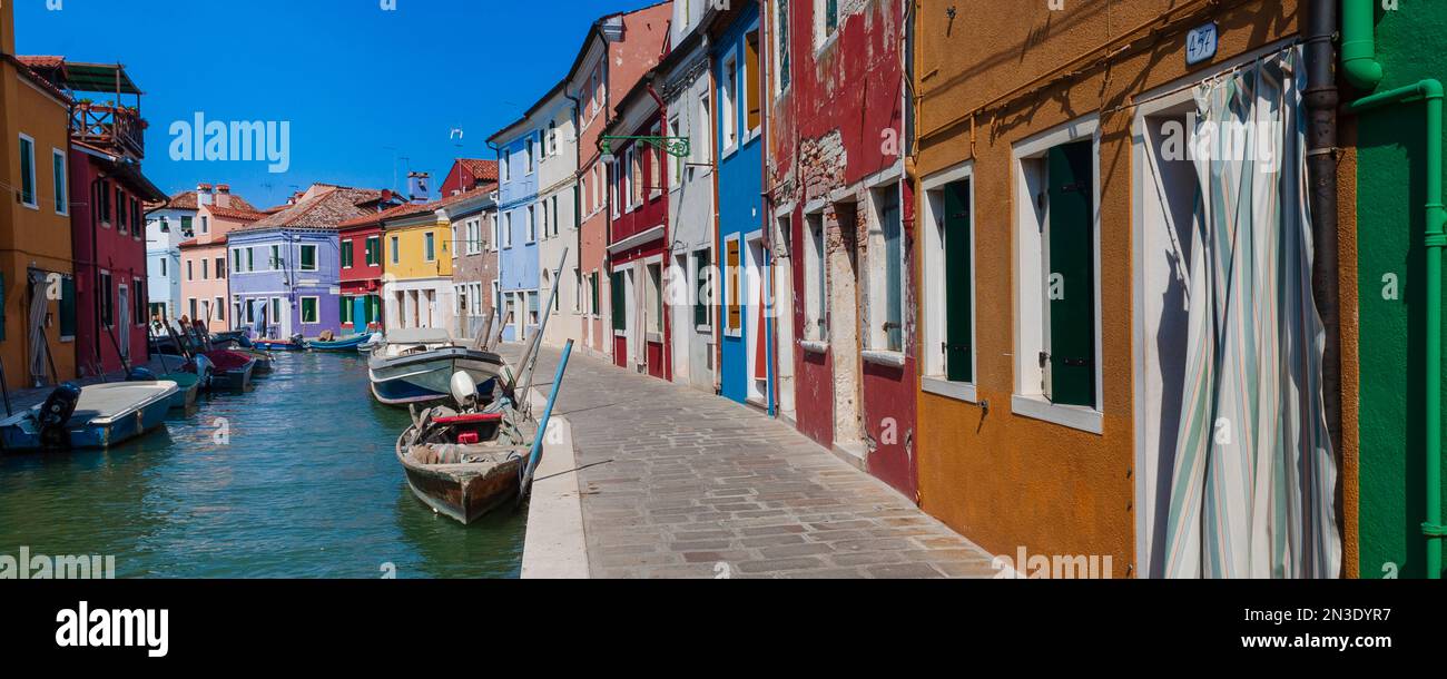 Colorful houses along the waterfront canal on Burano Island in Veneto; Venice, Italy Stock Photo