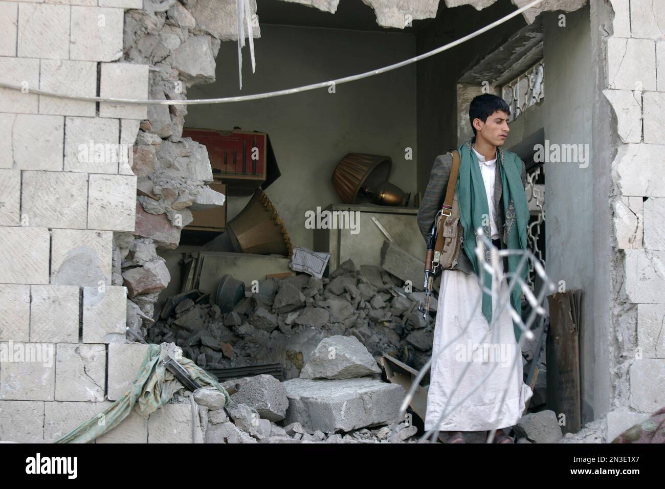 A Yemeni stands guard at the damaged residence of the Iranian