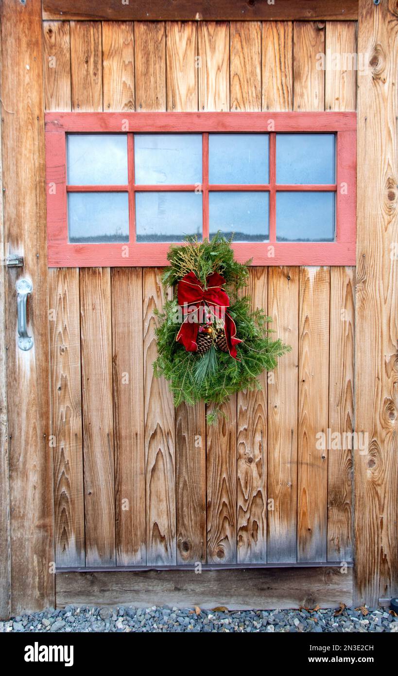 A homemade Holiday swag hanging on a barn door; Homer, Alaska, United States of America Stock Photo