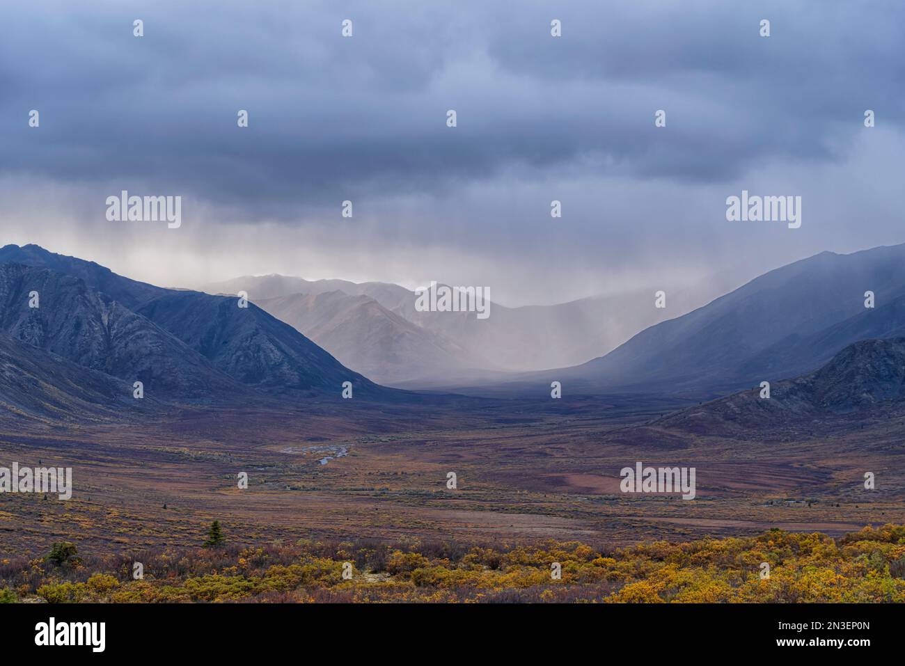 Rain clouds over mountains along the Dempster Highway create amazing landscapes while fall colors settle into the valley; Yukon, Canada Stock Photo