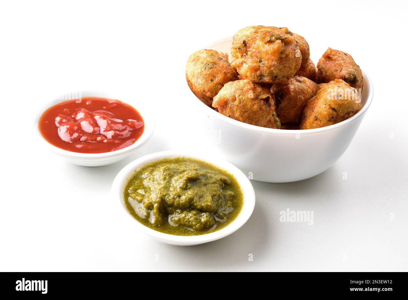 Moong dal pakora in bowl served with red and green chutney on white background Stock Photo