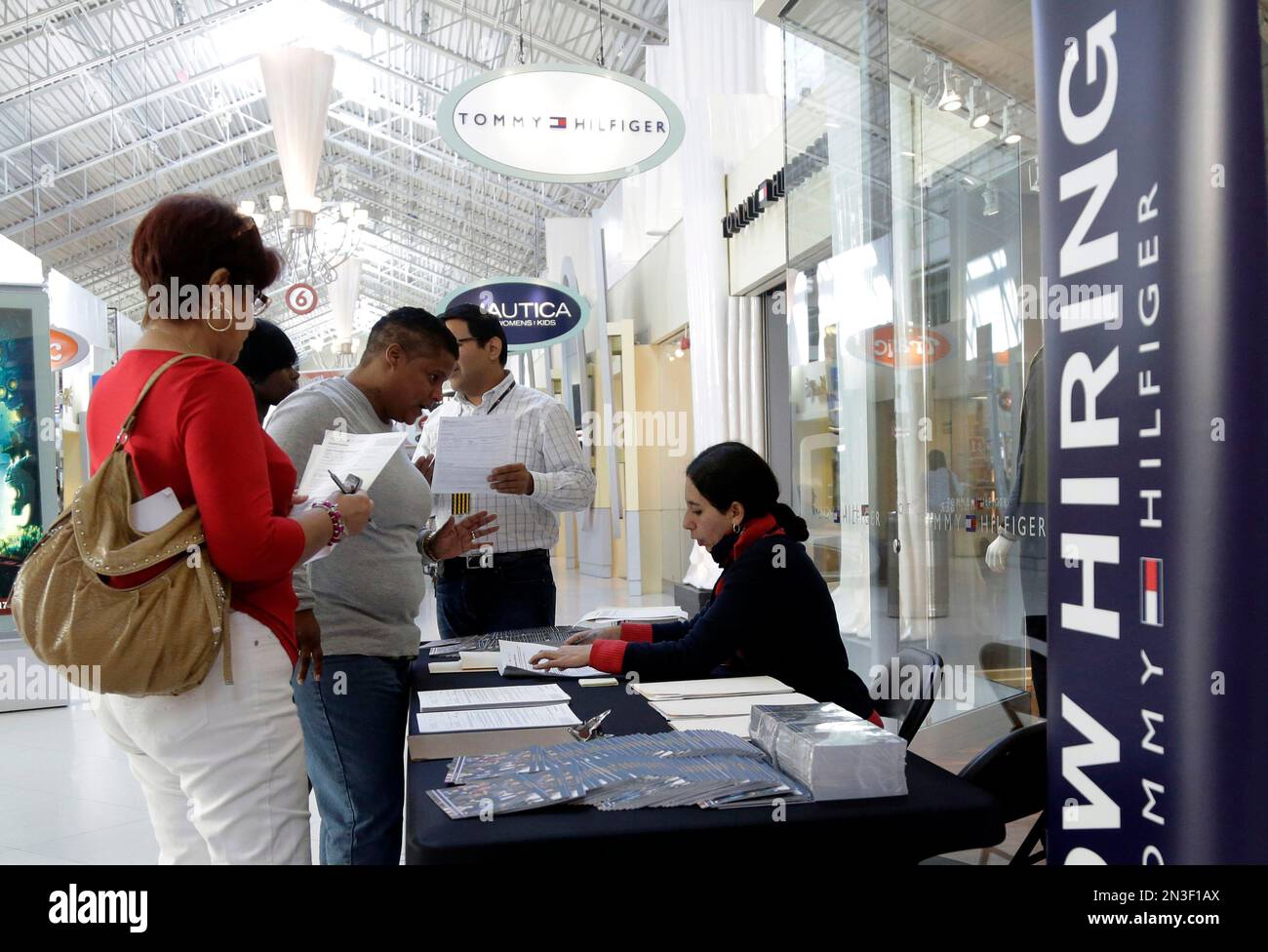 In this Oct. 28, 2014 photo, Tommy Hilfiger employee Sandra Hoyos, right,  talks with job applicants during a job fair at Dolphin Mall, in Miami.  Retailers are hiring workers for the upcoming