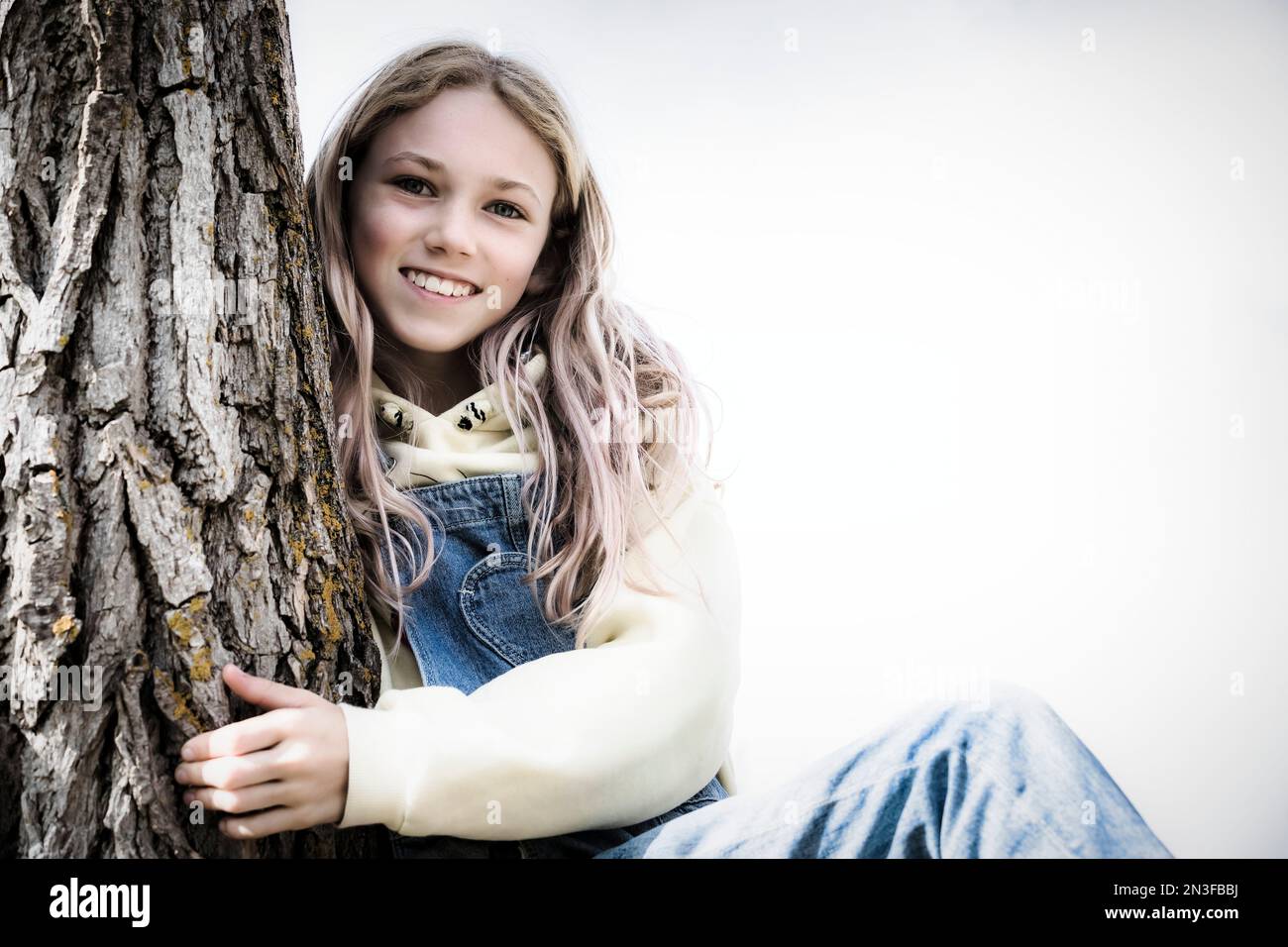 Portrait of a pre-teen girl beside a tree trunk; St. Albert, Alberta, Canada Stock Photo