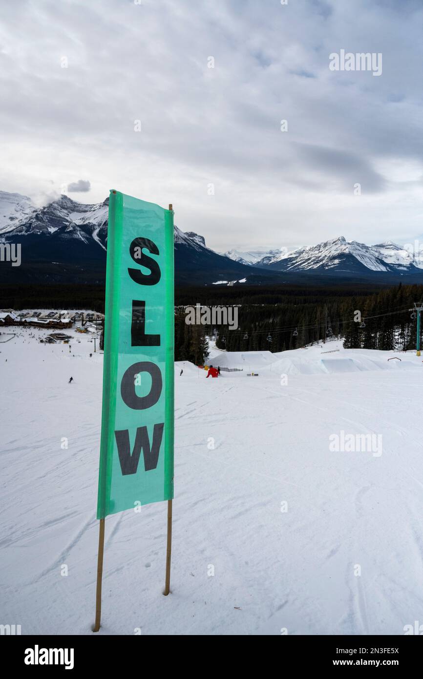 Sign to require slowing down towards the end of a ski run at a ski resort in Banff National Park, Alberta, Canada Stock Photo
