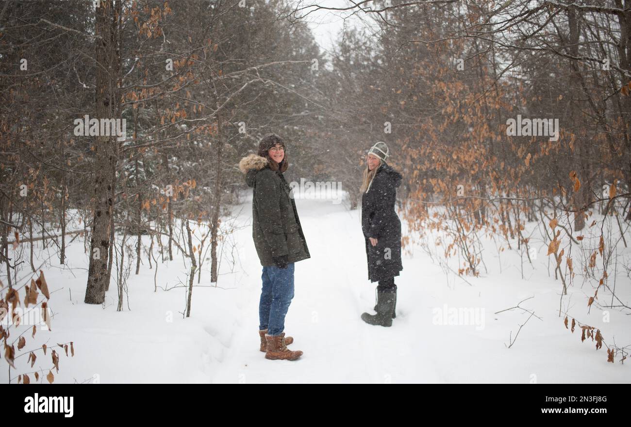 Two women walking together through the woods during a snowfall; Ottawa ...