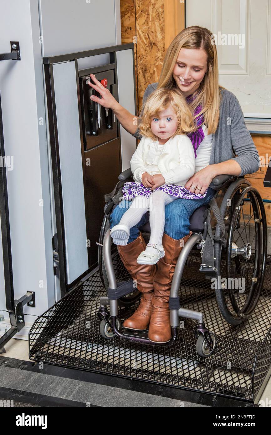 Young disabled mother with her daughter using a wheelchair powered device to assist with mobility; Spruce Grove, Alberta, Canada Stock Photo