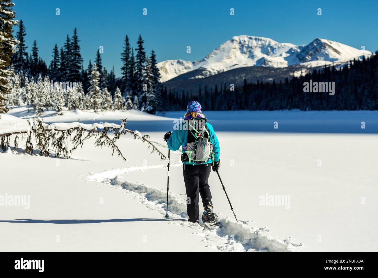 Female snowshoeing on a snowcovered lake with snowcovered Rocky