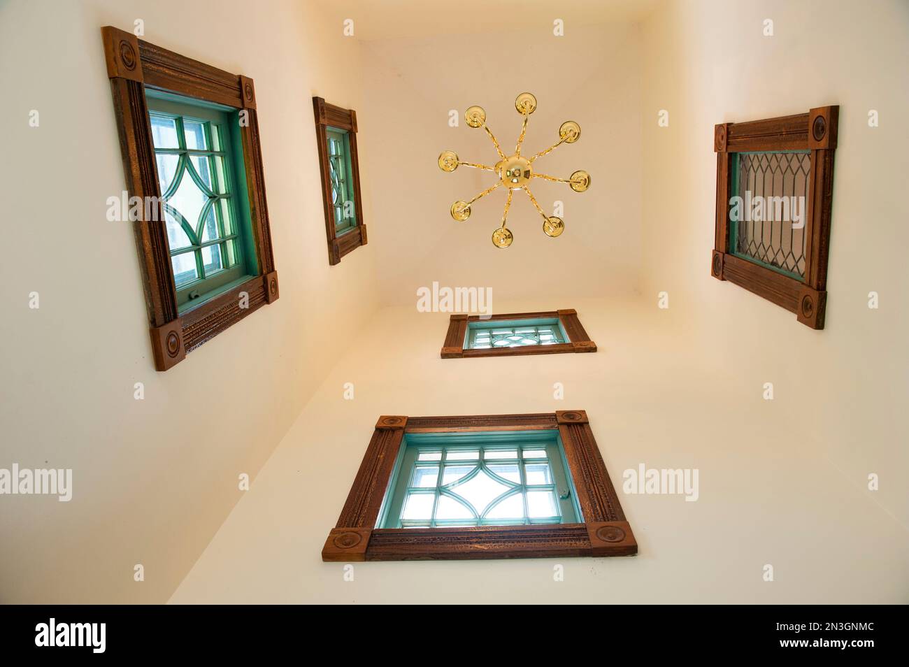 View from directly below of a ceiling and light fixture and a high wall with windows in a house; Waveland, Mississippi, United States of America Stock Photo