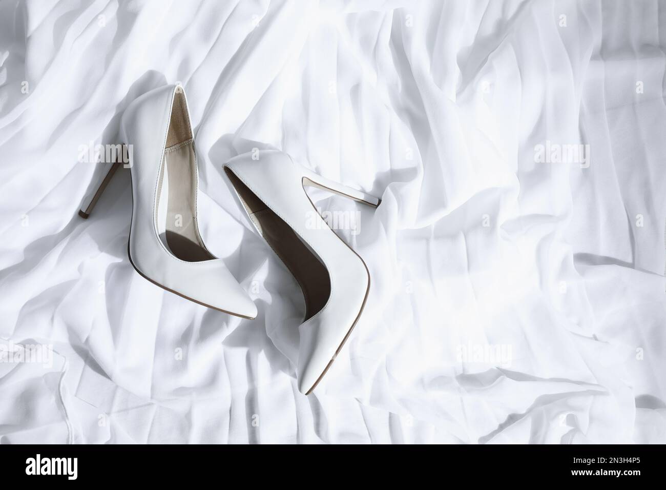 Pair of wedding high heel shoes on white fabric, above view Stock Photo