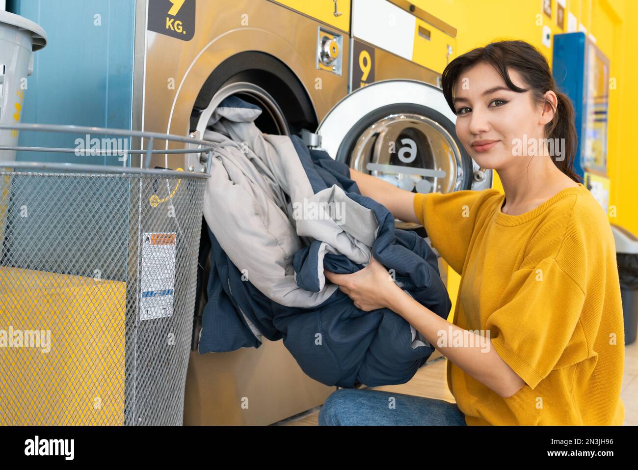 Asian people using qualified coin operated laundry machine in the public room to wash their cloths. Concept of a self service commercial laundry and Stock Photo
