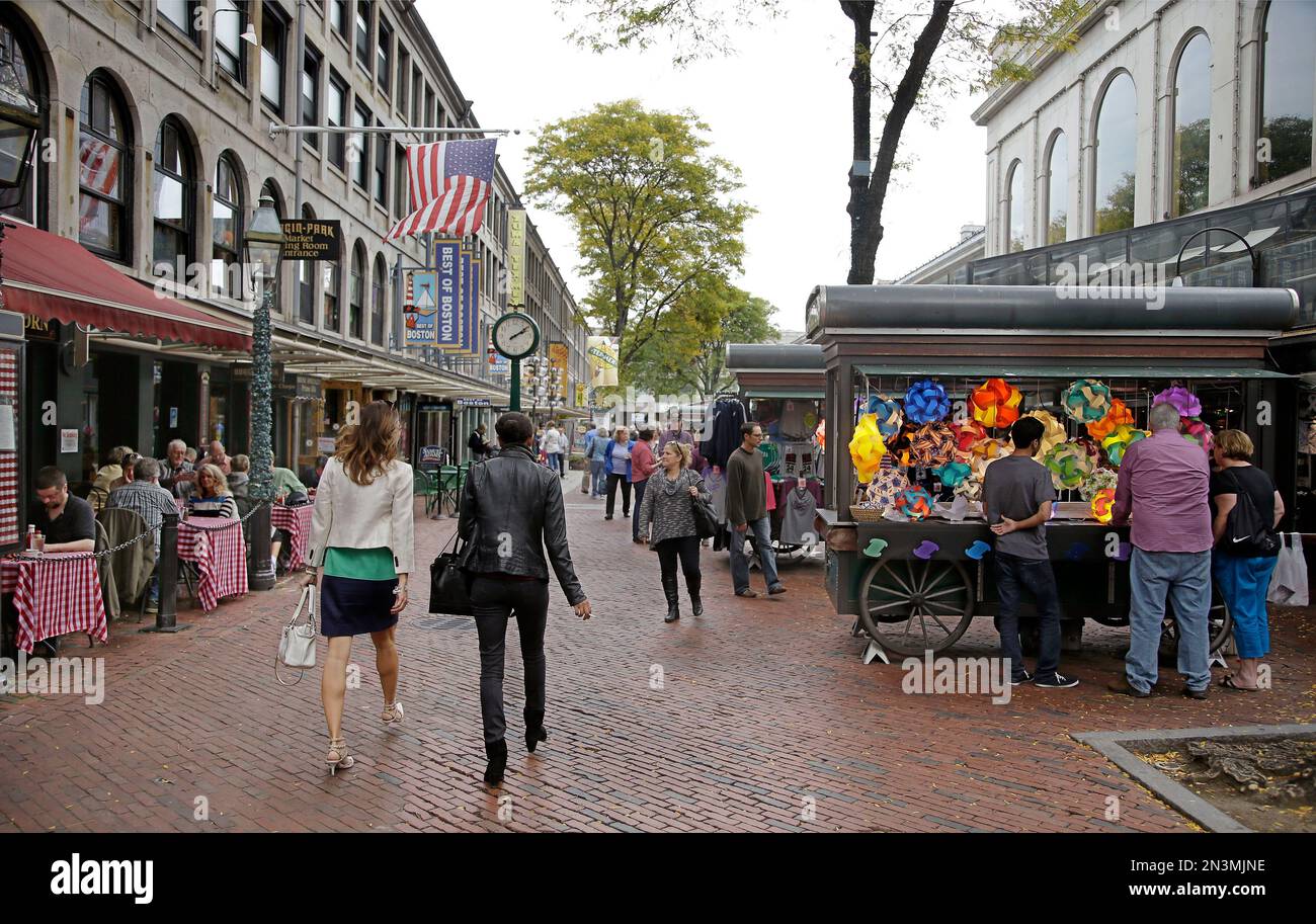 Visitors walk through Quincy Market as others eat lunch and shop