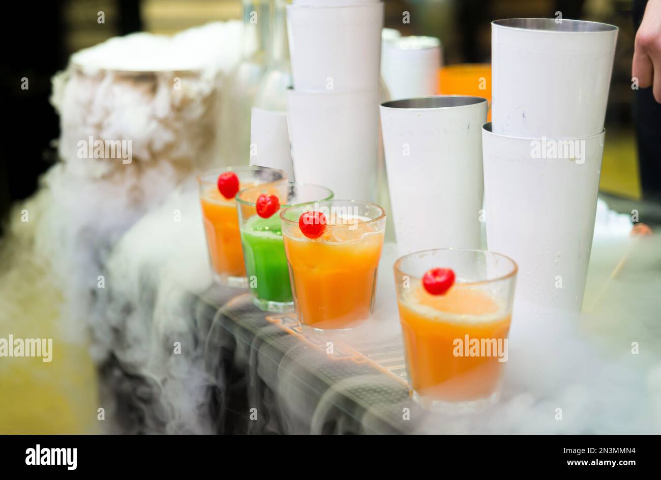 Colorful smoothies in glass cups for sale at a bar counter. In a cloud of nitrogen Stock Photo