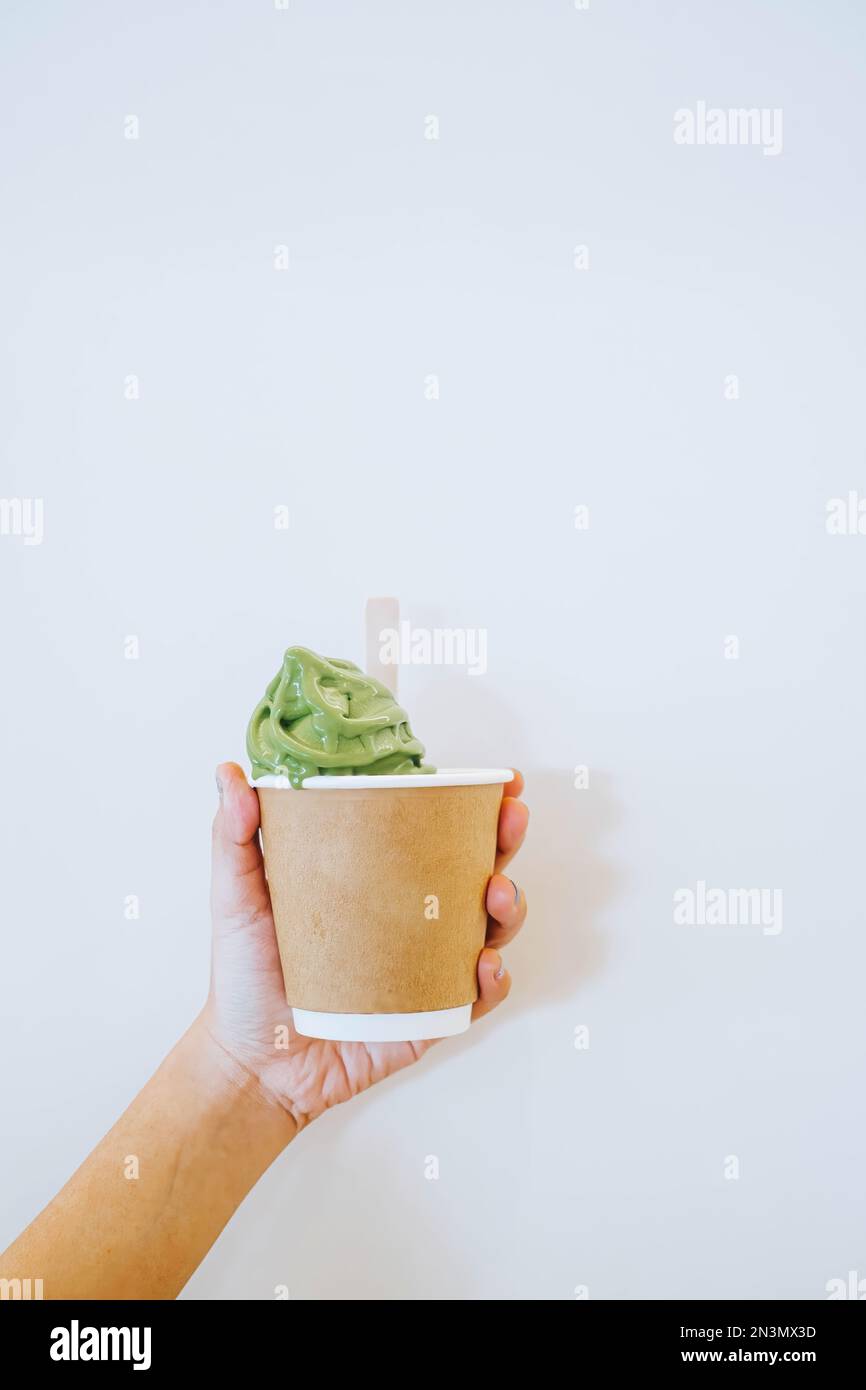 Delicious Japanese Matcha ice cream in a disposable cup made of cardboard and foam held by hand. Dessert. Hand holding. Eco-Friendly Concept. Stock Photo