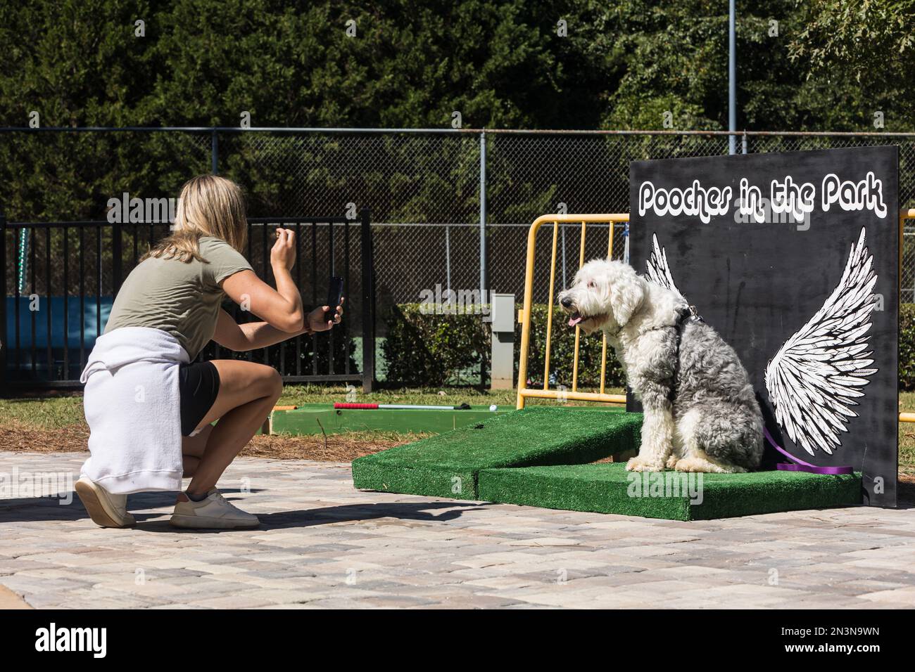Braselton, GA / USA September 24, 2022 A woman takes a photo of her dog against an angel wing